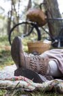 Pés e botas de tornozelo de mulher forager descansando sobre cobertor na floresta — Fotografia de Stock