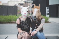 Retrato de pareja hippy punk con conejo y máscaras de disfraces de caballo - foto de stock