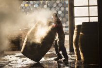Male cooper working in cooperage with whisky casks — Stock Photo
