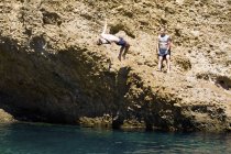 Двое молодых людей, ныряющих в море со скал, Марсель, Франция — стоковое фото