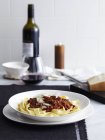 Bolognese-Sauce mit Tagliatelle und Rotwein im Hintergrund — Stockfoto