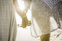Mother and daughter holding hands on beach — Stock Photo