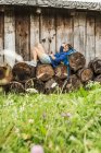 Woman resting on stack of cut logs — Stock Photo