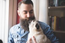 Молодой бородатый мужчина с собакой на руках — стоковое фото
