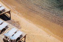 Sun loungers on sandy beach, elevated view — Stock Photo