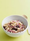 Bowl of beans salad with olives and red onion slices — Stock Photo