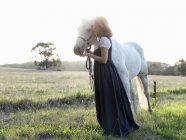 Retrato de menina adolescente com cavalo cinza no campo iluminado pelo sol — Fotografia de Stock
