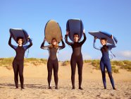 Quatre surfeuses debout sur une plage — Photo de stock
