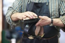 Male worker in leather workshop, polishing belt, mid section — Stock Photo