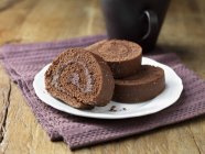 Plato de rollos de esponja de chocolate en servilleta de tela púrpura - foto de stock