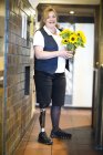 Retrato de mulher adulta média com perna protética, em pé, segurando flores — Fotografia de Stock