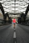 Молода жінка бігунка перетинає міст — стокове фото
