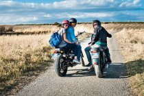 Vista posteriore di tre amici in moto su strada rurale, Cagliari, Sardegna, Italia — Foto stock
