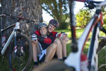 Cyclists resting by tree — Stock Photo