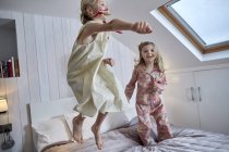 Mädchen springen auf Bett im Dachgeschoss — Stockfoto