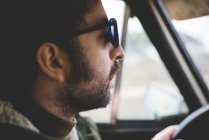 Крупный план среднего взрослого мужчины за рулем и в солнечных очках — стоковое фото