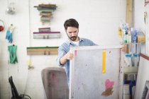 Junge männliche Drucker betrachten Leinwand in Druckereistudio — Stockfoto