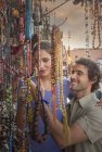 Parejas jóvenes en el mercado mirando perlas, Plaza Jemaa el-Fnaa, Marrakech, Marruecos - foto de stock