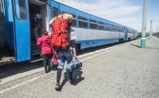 Visão traseira de jovens caminhantes com mochilas embarcando em um trem — Fotografia de Stock