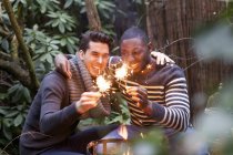 Two young men crouching in front of garden fire with sparklers — Stock Photo