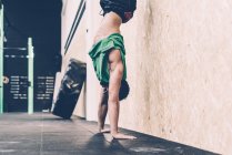 Young male cross trainer doing handstand in gym — Stock Photo