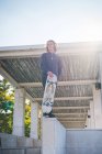 Retrato de jovem homem skatista urbano em pé na parede com skate — Fotografia de Stock