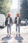 Young male hipster twins with red hair and beards strolling on city road — Stock Photo