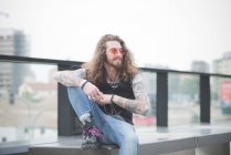 Portrait of young man with long hair and sunglasses — Stock Photo
