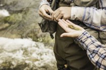 Cropped view of woman handing man fishing fly — Stock Photo