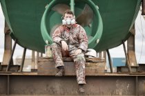 Portrait of male ship painter wearing protective mask in front of green ship hull in ship painters yard — Stock Photo