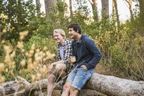 Two hikers leaning against fallen tree in forest, Deer Park, Cape Town, South Africa — Stock Photo