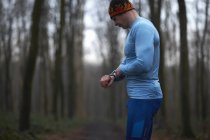 Runner wearing knit hat and spandex looking down at wrist watch — Stock Photo