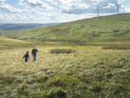 Brothers walk up hill together at windfarm — Stock Photo