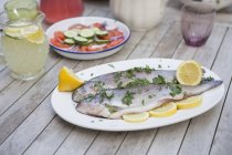 Raw trouts with herbs and lemon slices on plate — Stock Photo