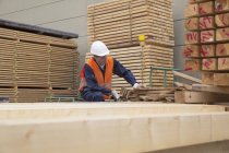 Holzarbeiter sortiert Holzbohlen im Bauhof — Stockfoto