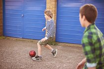 Due ragazzi che giocano a calcio da garage porte blu — Foto stock