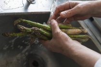 Colpo ritagliato di persona che lava gli asparagi, concentrarsi sulle mani — Foto stock