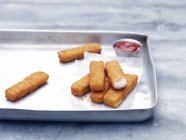 Teglia con fritto grosso merluzzo impanato dita di pesce con ketchup di pomodoro — Foto stock