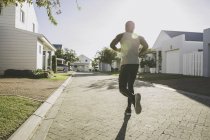 Vue arrière du jogging de l'homme dans un quartier résidentiel — Photo de stock