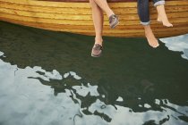 Feet of middle aged couple sitting on boat over water — Stock Photo