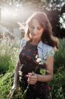 Donna che raccoglie fiori nel prato illuminato dal sole — Foto stock
