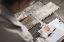 Carpintero midiendo tablón de madera con pinza vernier en fábrica - foto de stock