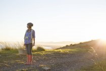 Jovem mulher de pé na colina ao pôr do sol — Fotografia de Stock