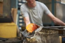 Glassblower in workshop forming molten glass on blowpipe — Stock Photo