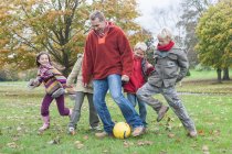 Father and children, playing football in park — Stock Photo