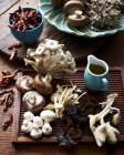 Various mushrooms on wooden board and dried chillis in bowl — Stock Photo