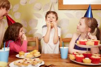 Niños comiendo comida de fiesta en la fiesta de cumpleaños - foto de stock