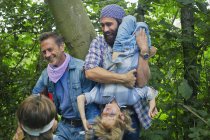 Dos hombres adultos y dos niños disfrazados y jugando en el bosque - foto de stock