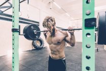 Junge männliche Crosstrainer Gewichtheben Langhantel in der Turnhalle — Stockfoto