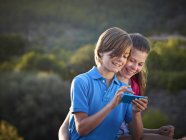Hermano y hermana adolescente usando pantalla táctil en smartphone, Mallorca, España - foto de stock